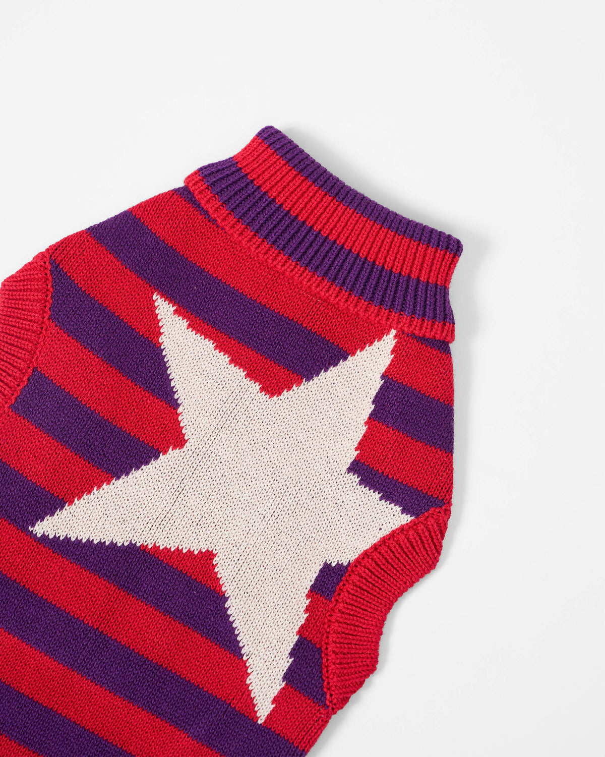 Close-up of a white star on a red and purple Cosmic Canine dog sweater.