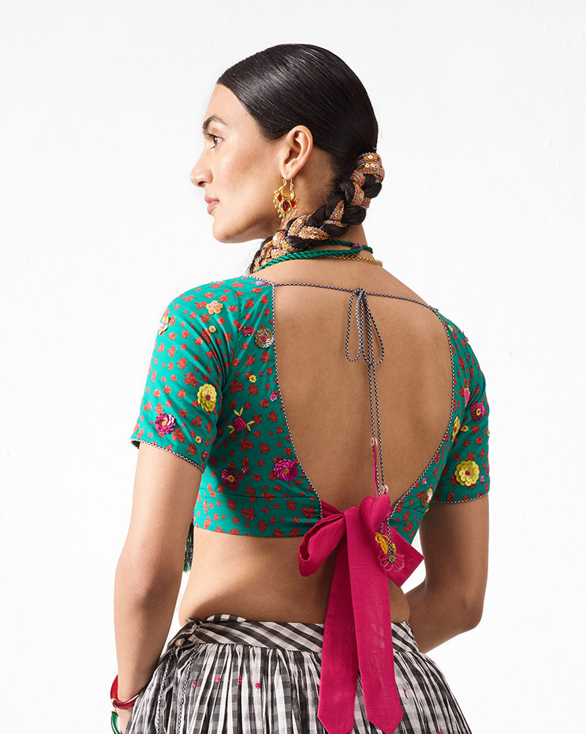 Back of a green Saanjh blouse with a red floral print and pink tie-back.