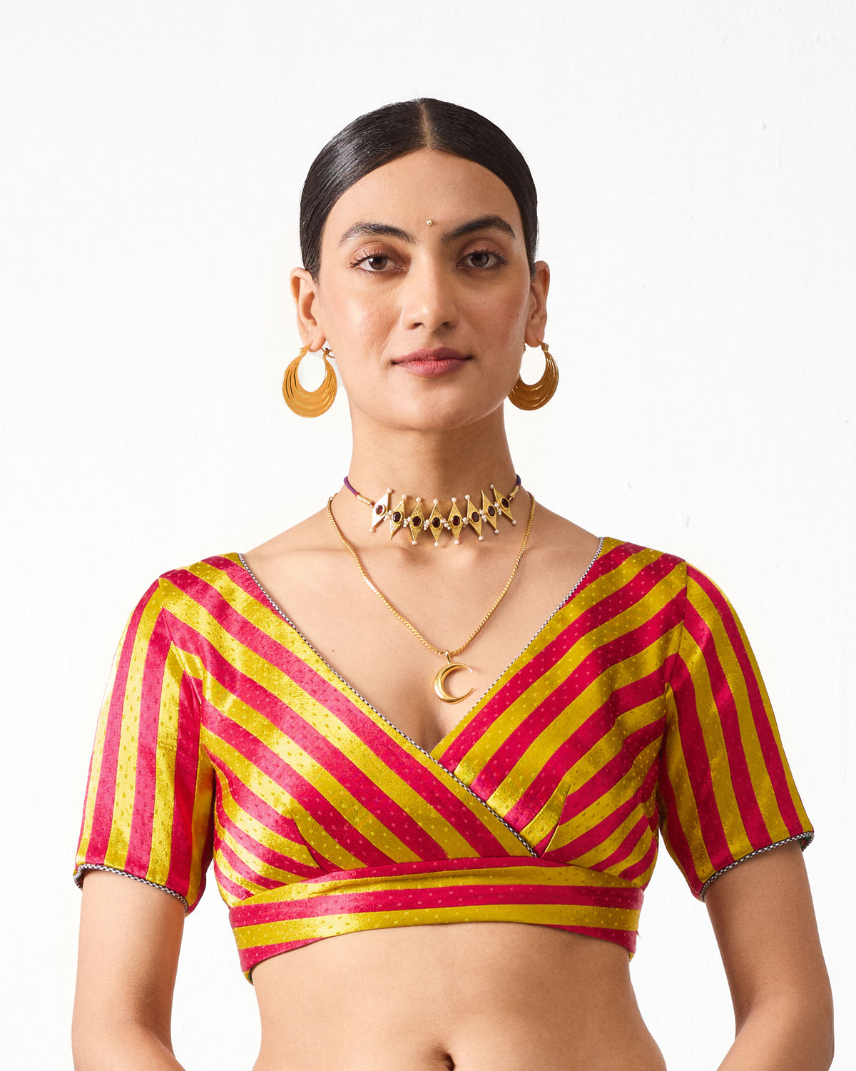 Person wearing the Zahra blouse in yellow and fuchsia stripes with a V-neck.