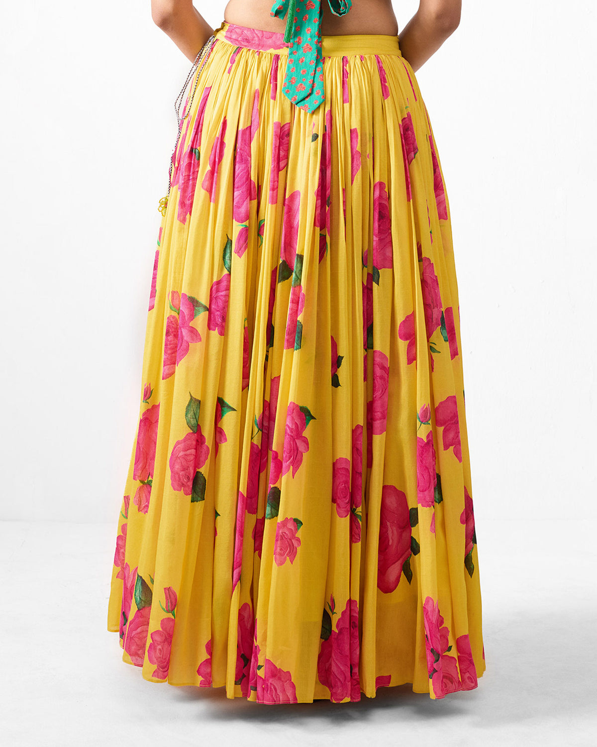 Back of a yellow Reha skirt with a pink rose print worn by a person.