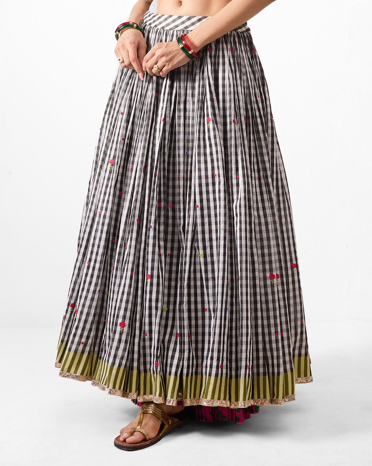 Person wearing a black and white gingham Sitara skirt with an olive striped hem.
