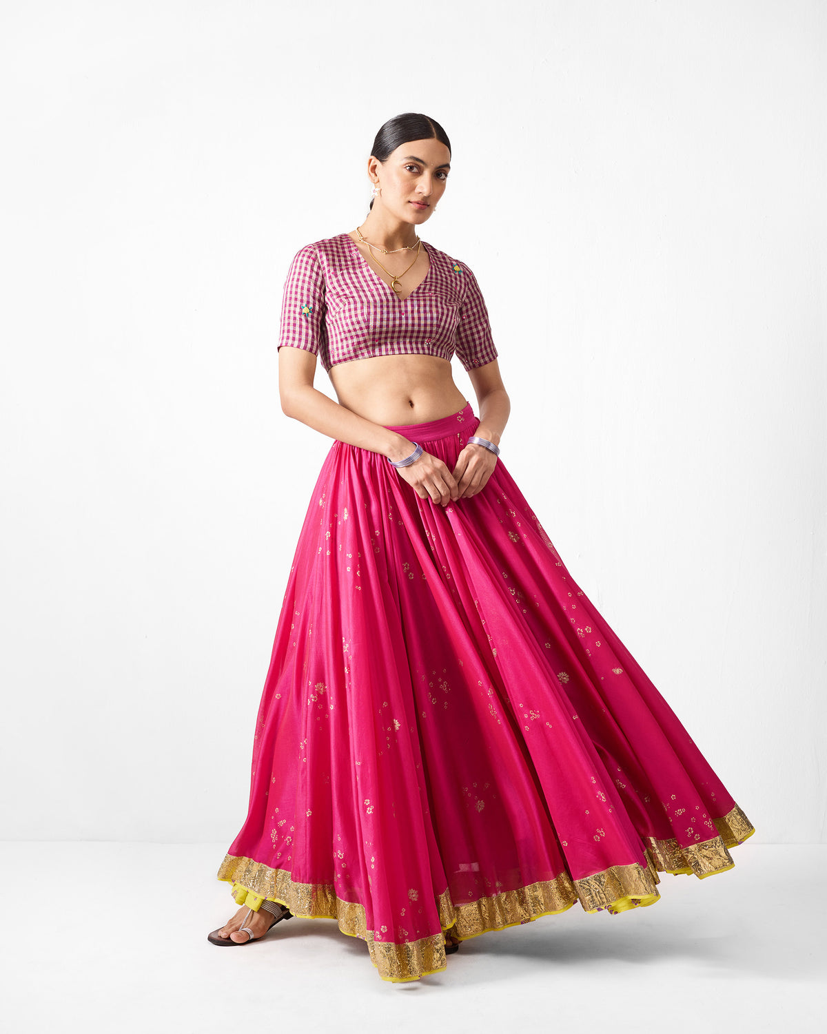 Person wearing a fuchsia Saaya skirt with gold print and a wide gold border.