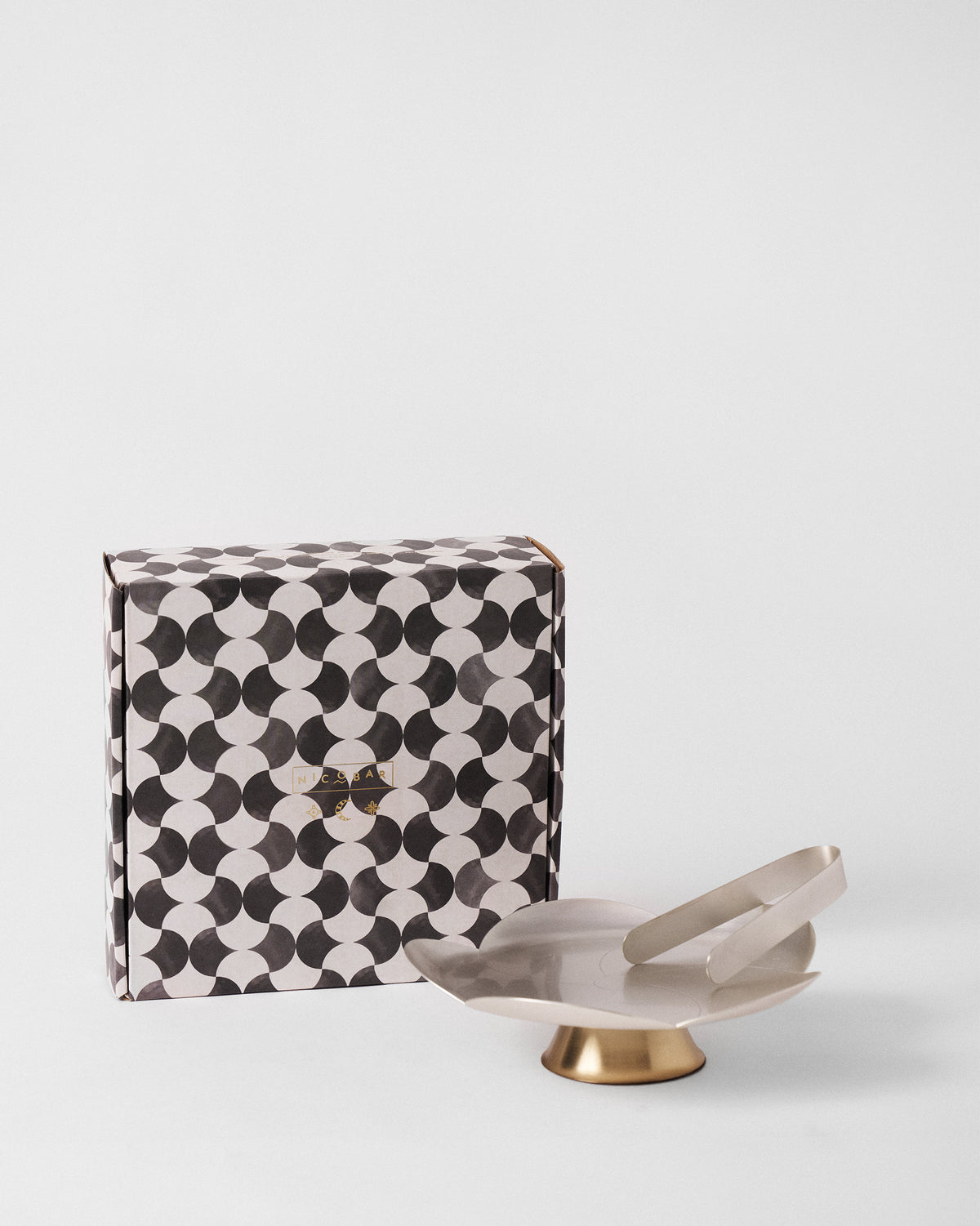 Almond Blossom Platter With Tong on a gold footed base, beside its patterned box.
