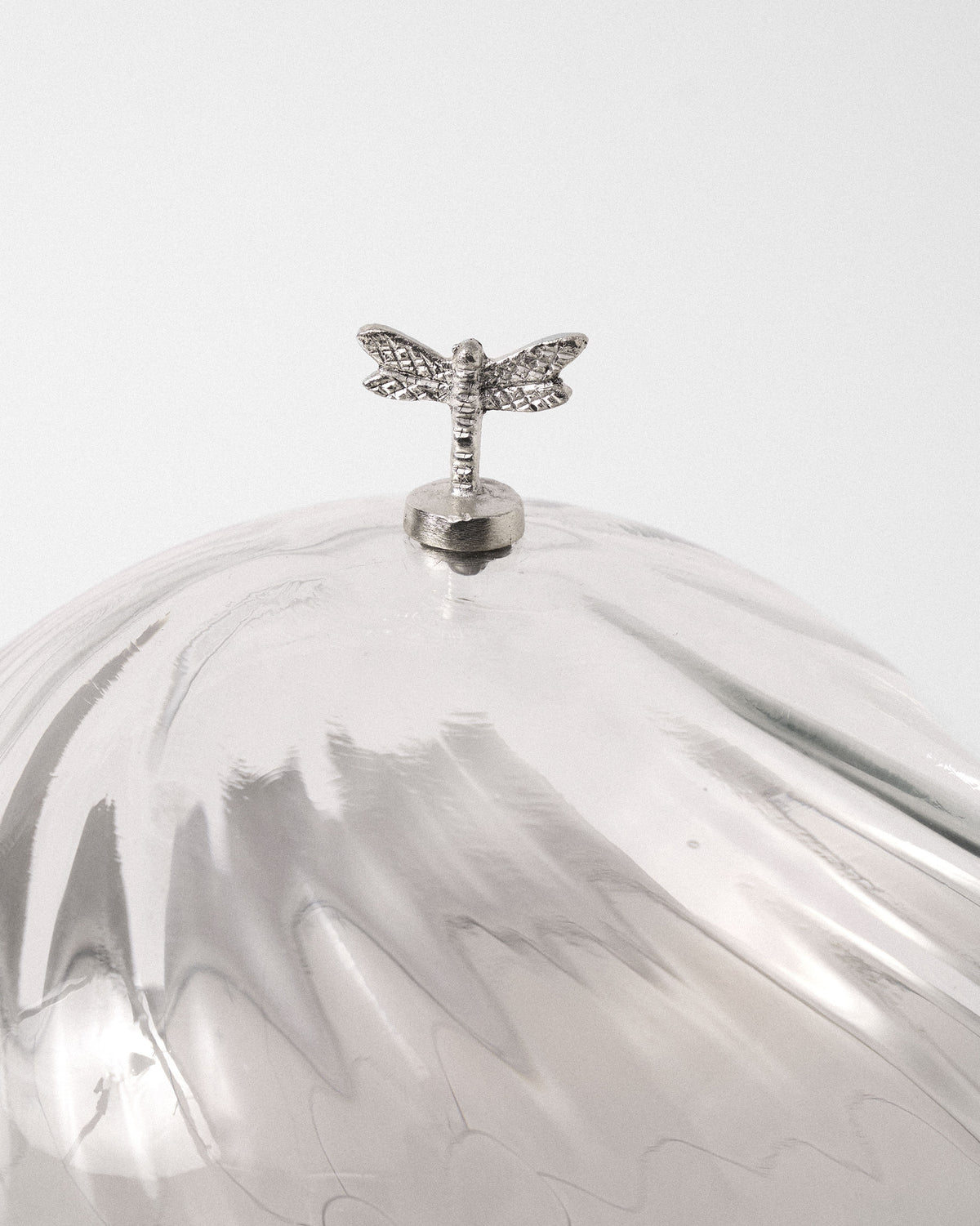 Close-up of the silver dragonfly knob on the ribbed glass Almond Blossom Cloche.