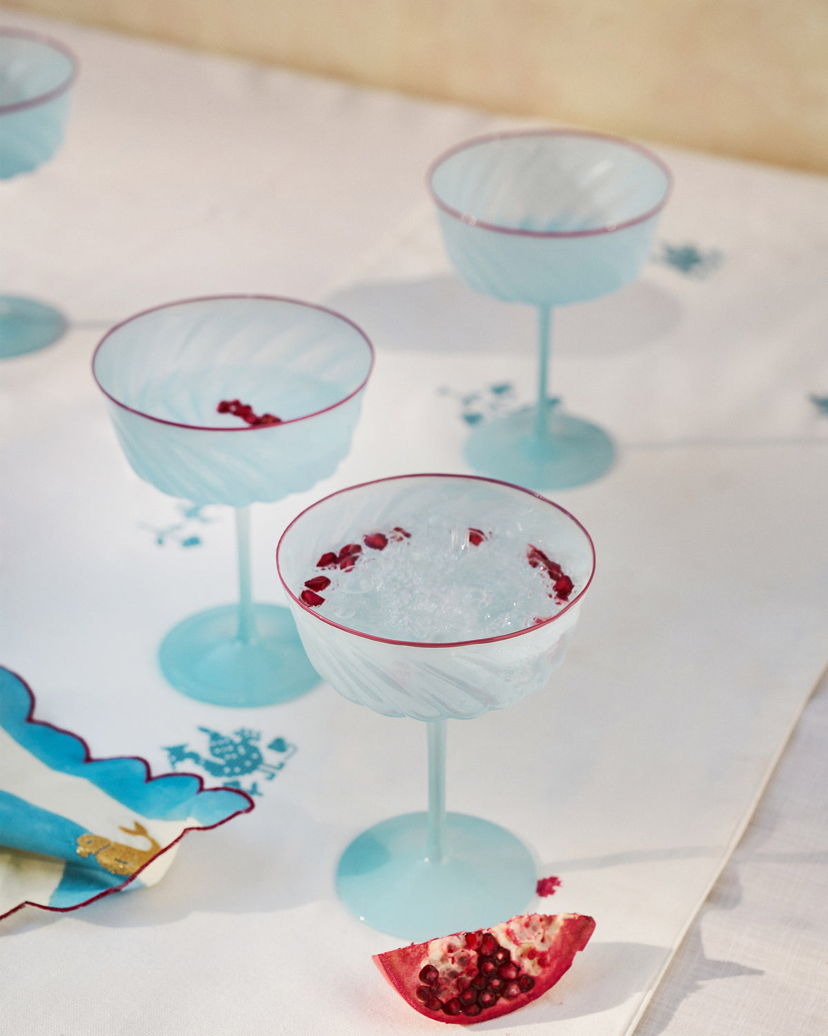 Ripple Margarita Glasses with pale blue swirled bowls and red rims, set on a table.