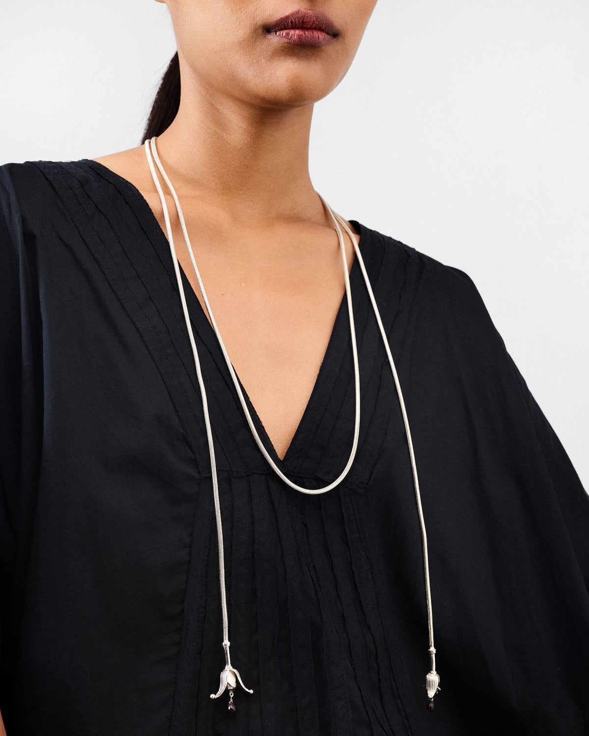 Person wearing a silver Phool chain with bell-shaped tassels at the chest.