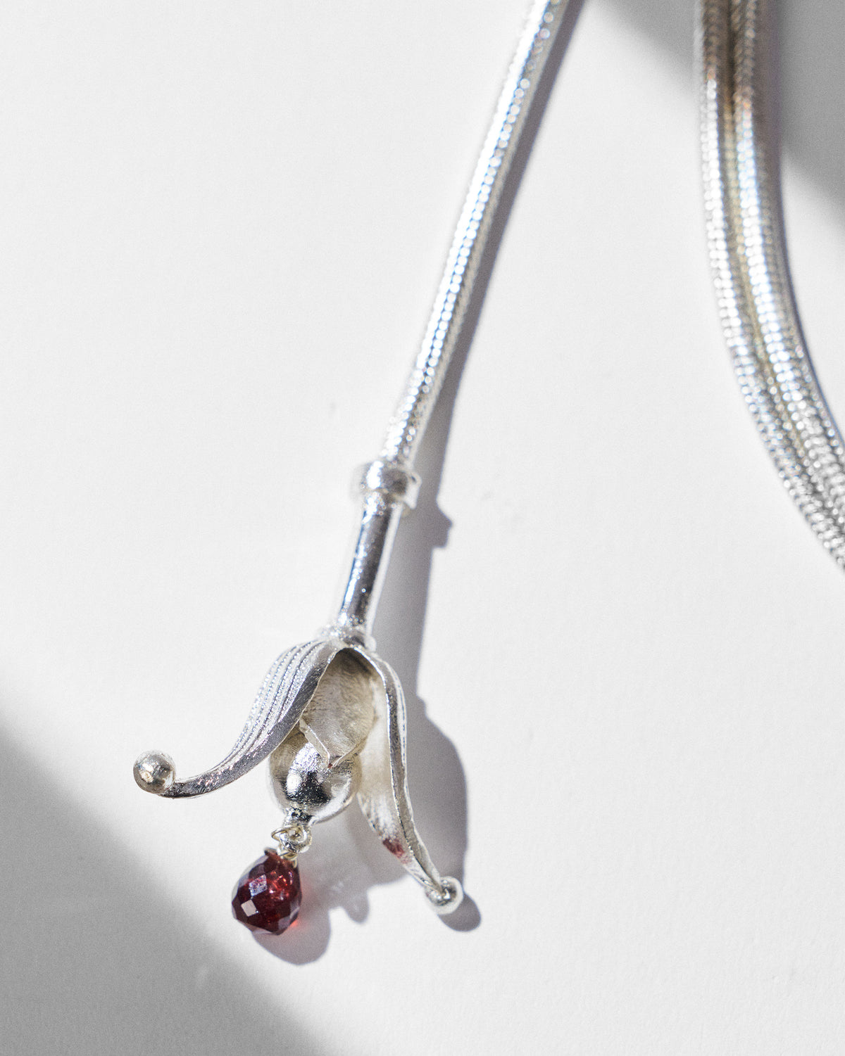 Close-up of a silver bell-shaped tassel with a red drop on the Phool chain.