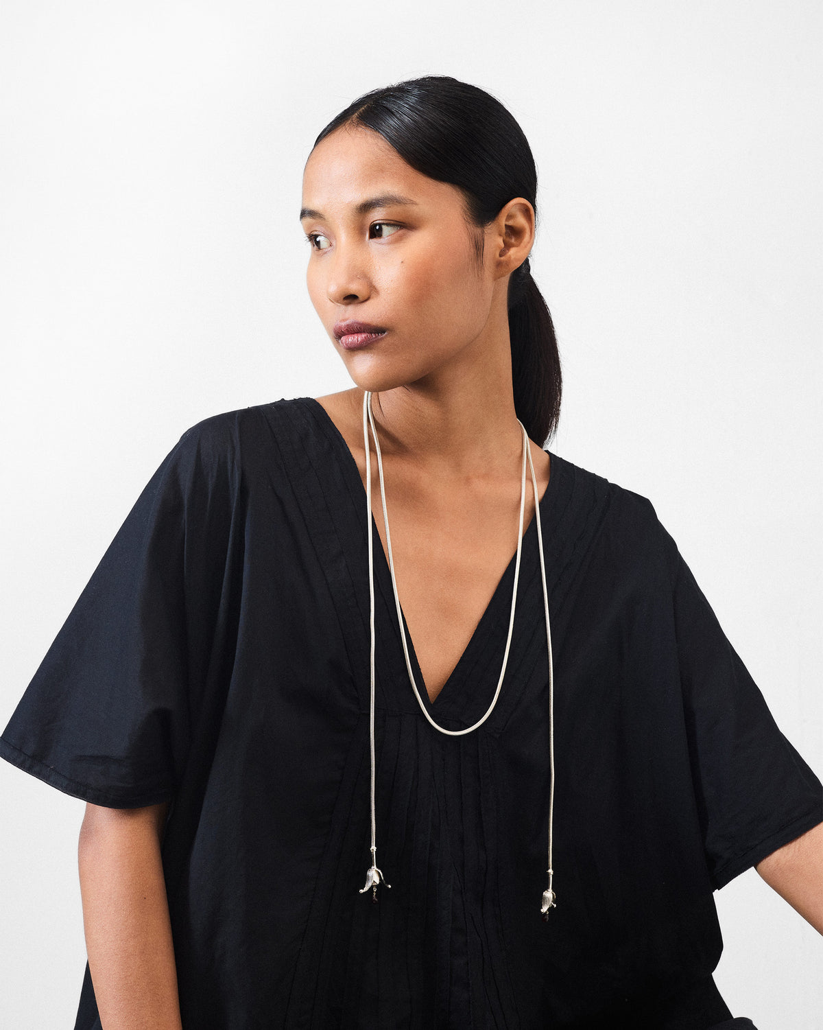 Side view of a person wearing a long silver Phool chain with tassels.