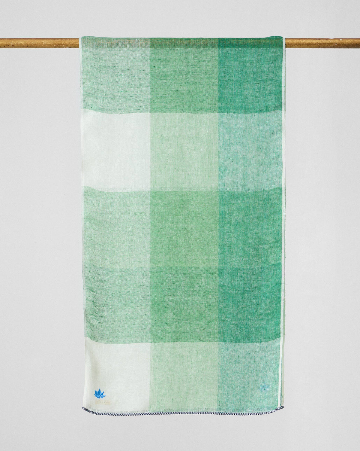 Summer Field Scarf hung from a rod in large green and white check blocks.