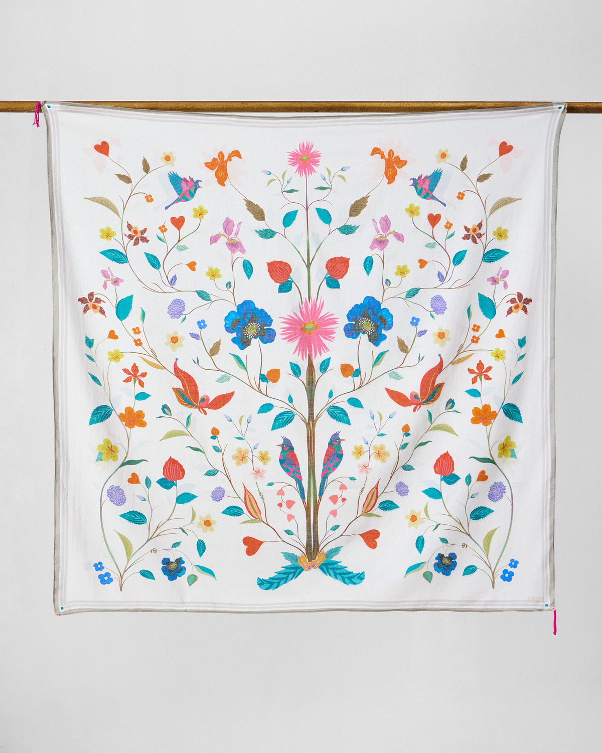 Jaal Scarf in white with multicolour floral motifs, hung from a rod.
