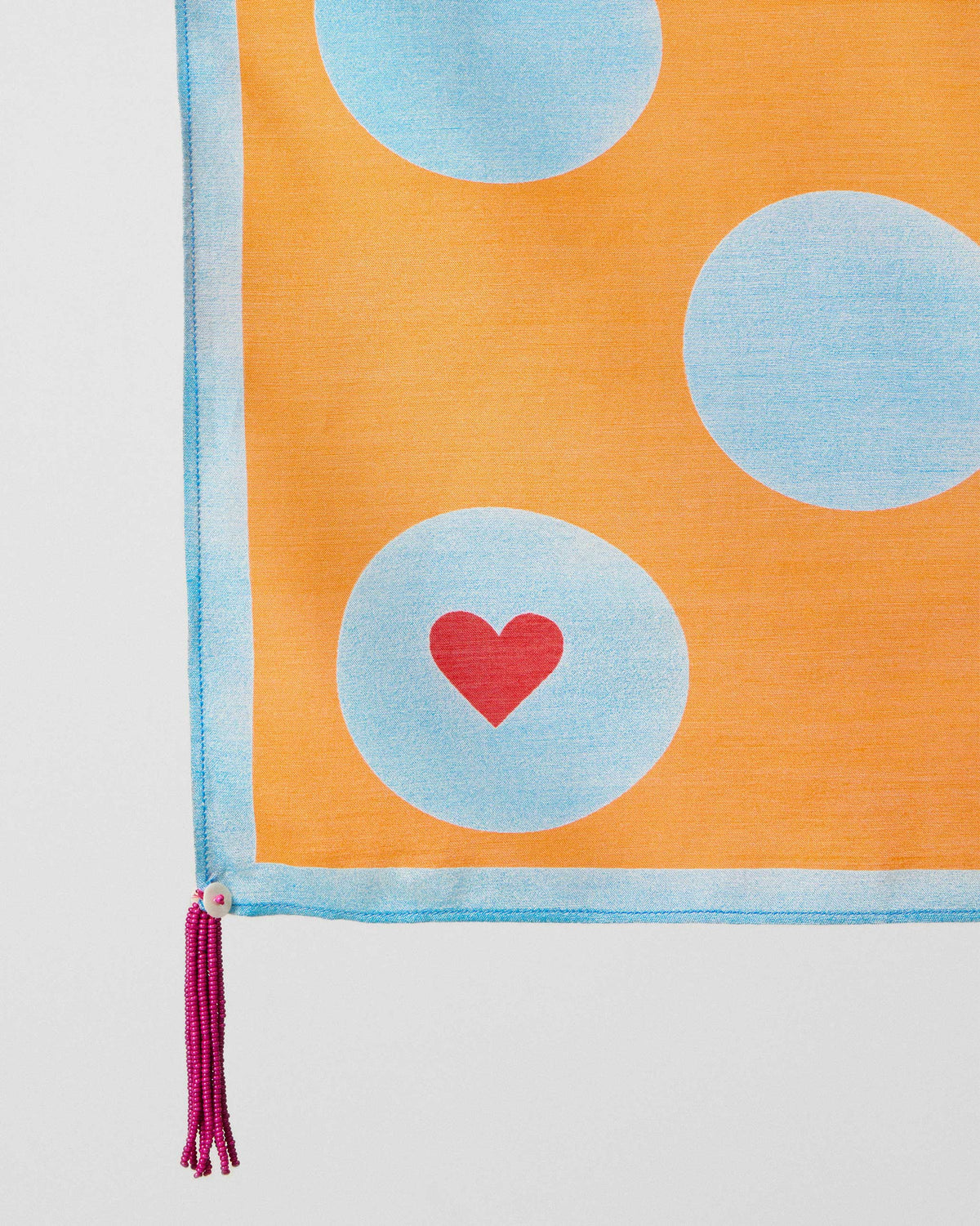 Close-up of a Dotty scarf corner showing a red heart on an ice blue dot.
