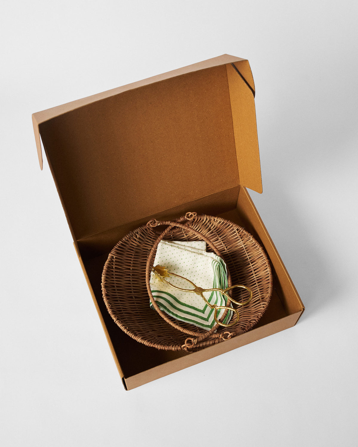 Rattan bread basket set nested in an open brown gift box.