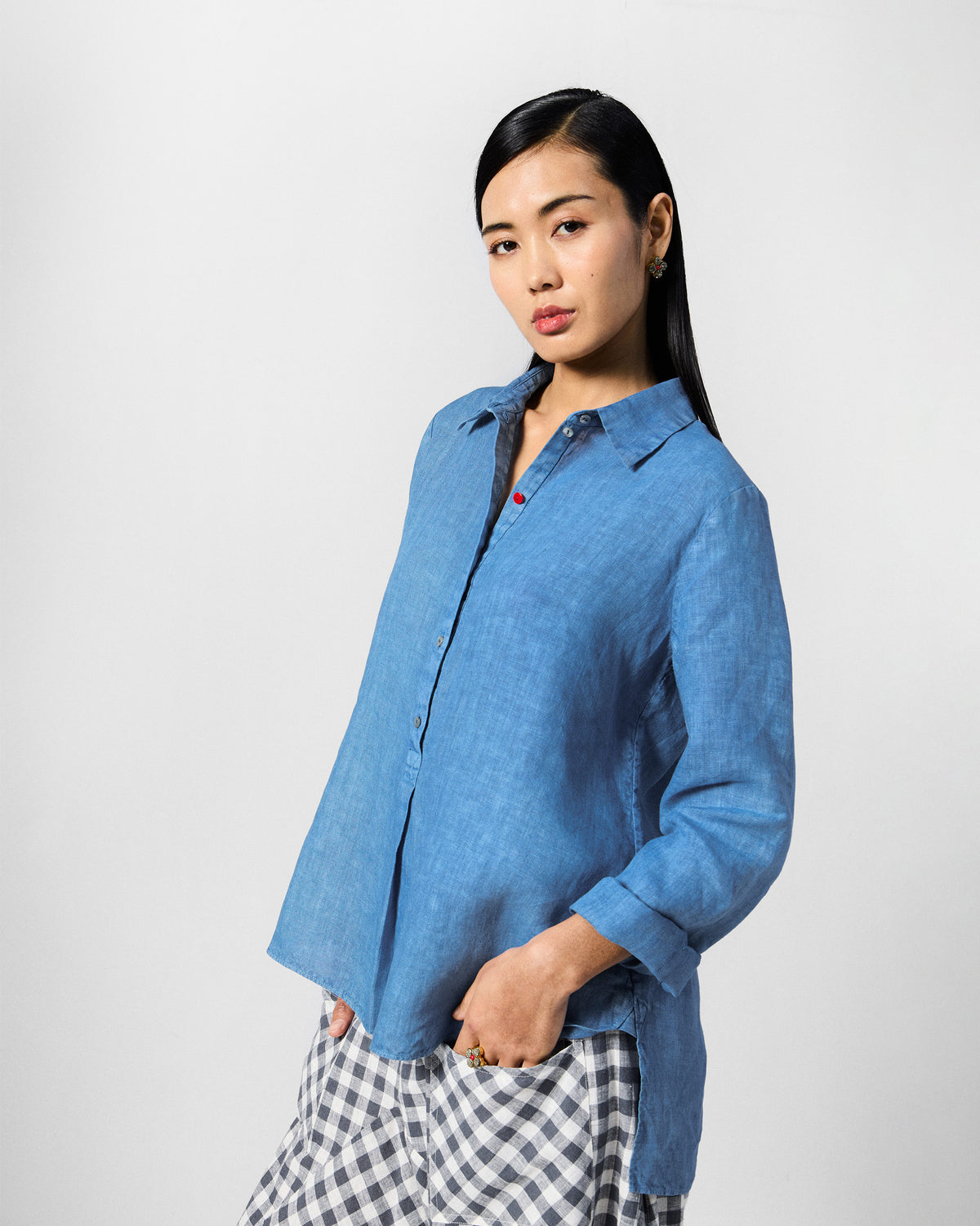 Person wearing a blue Mati shirt with a red button on the placket.