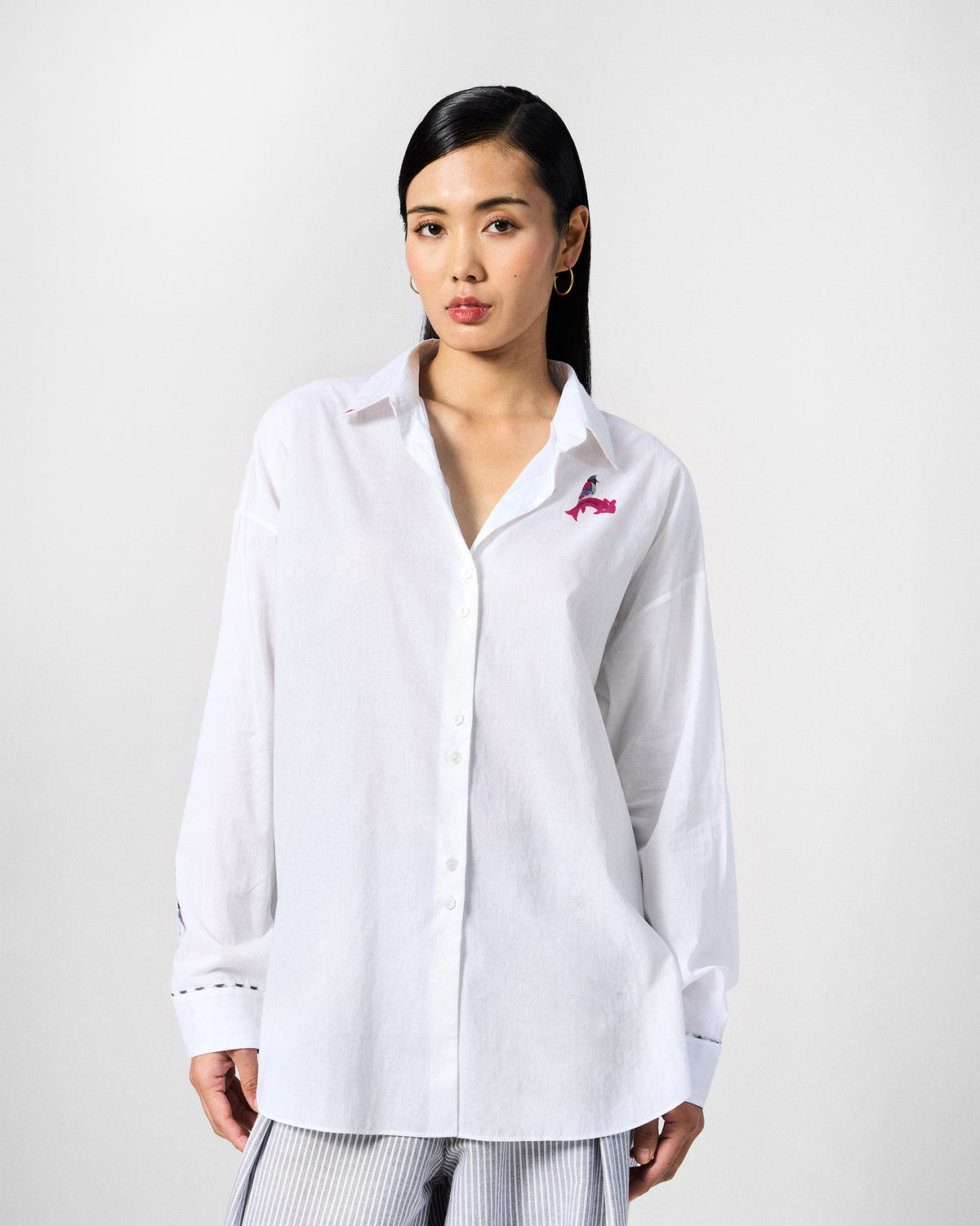Person wearing a white Siv shirt with a small pink chest motif.