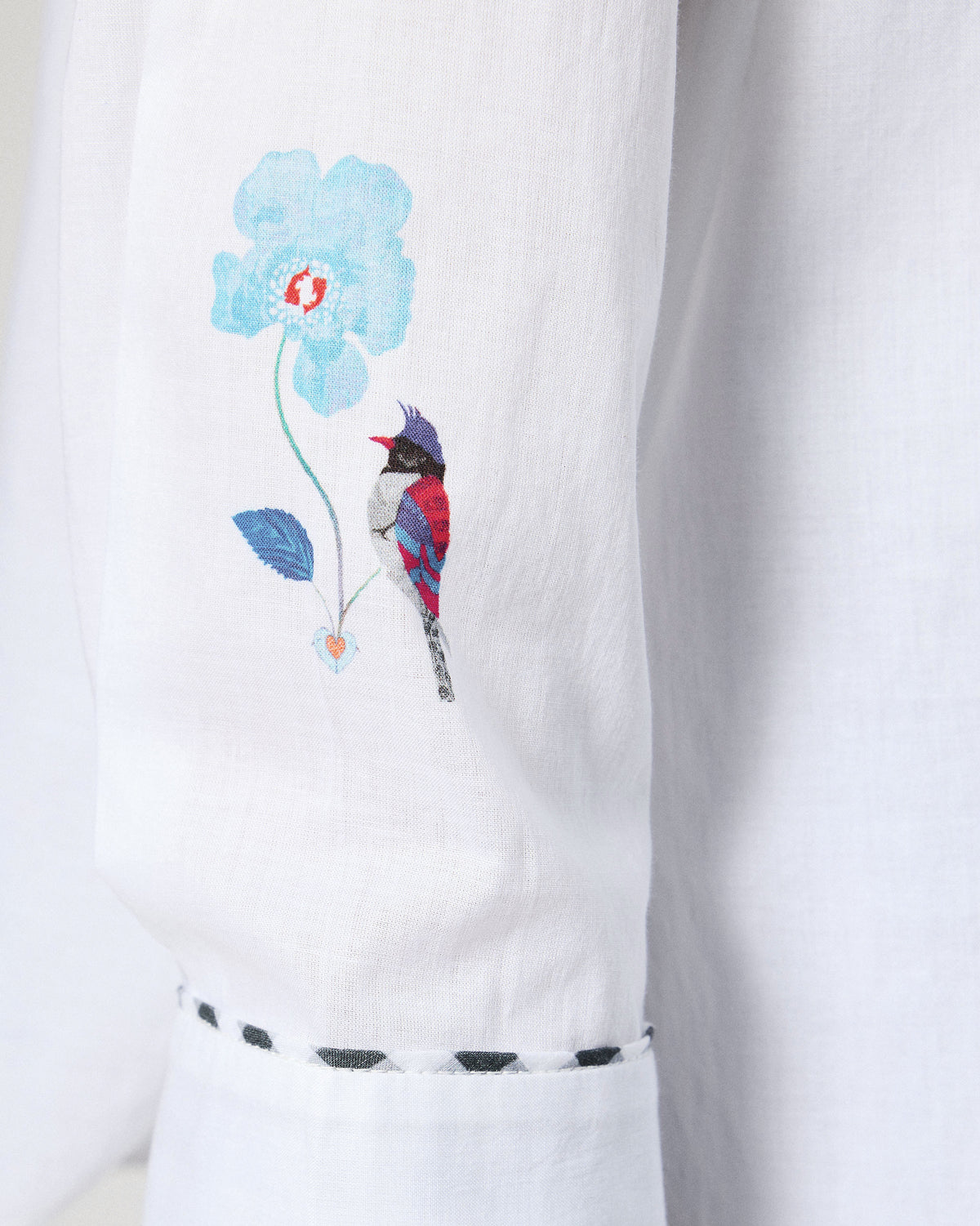 Close-up of bird embroidery on a white Siv shirt sleeve with a check cuff.