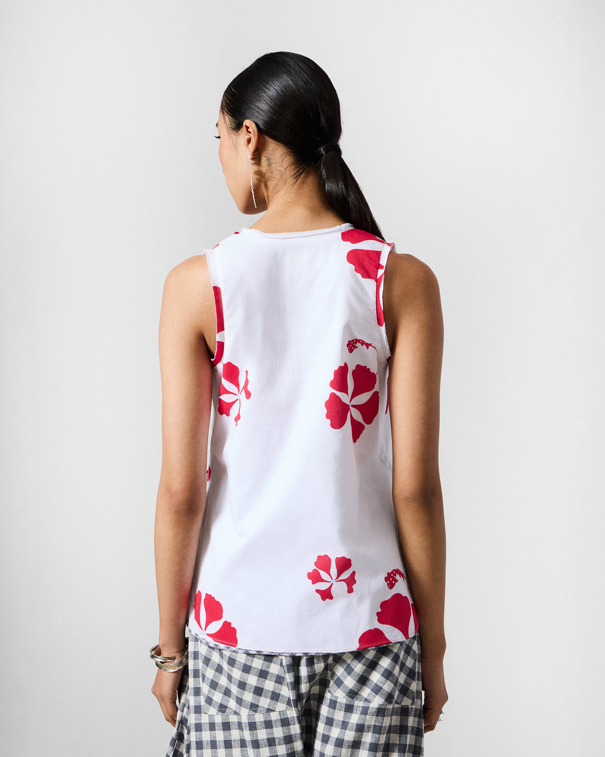 Back of a white Kiva top with red hibiscus flowers.