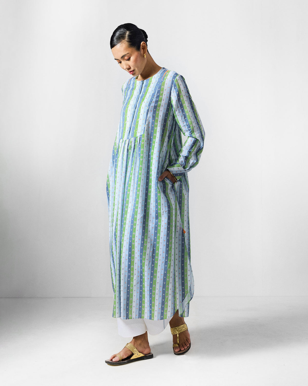 Person in profile wearing an Imke Kurta with a hand in its side pocket.