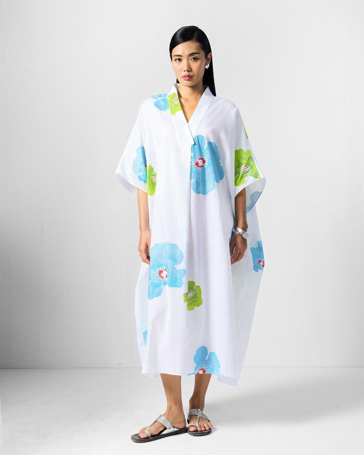 Person wearing a white Bea kaftan with a V-neck and floral print.