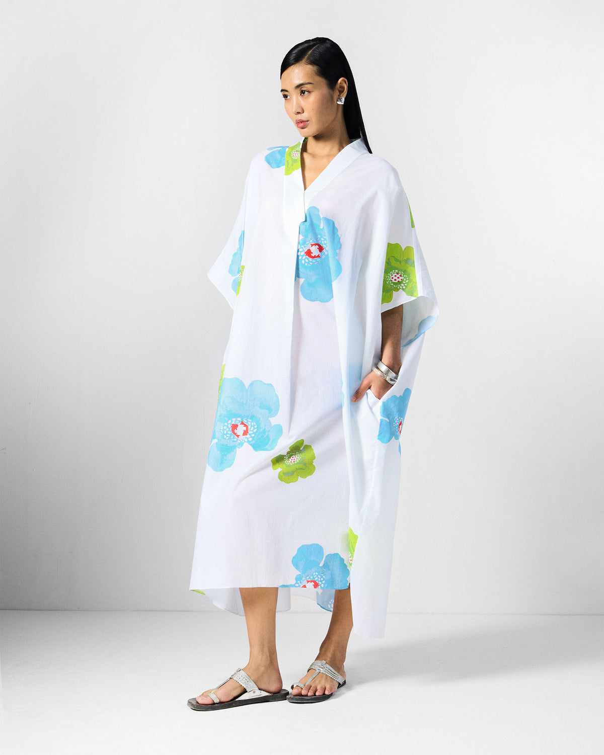 Person wearing a white Bea kaftan with a hand in the side pocket.