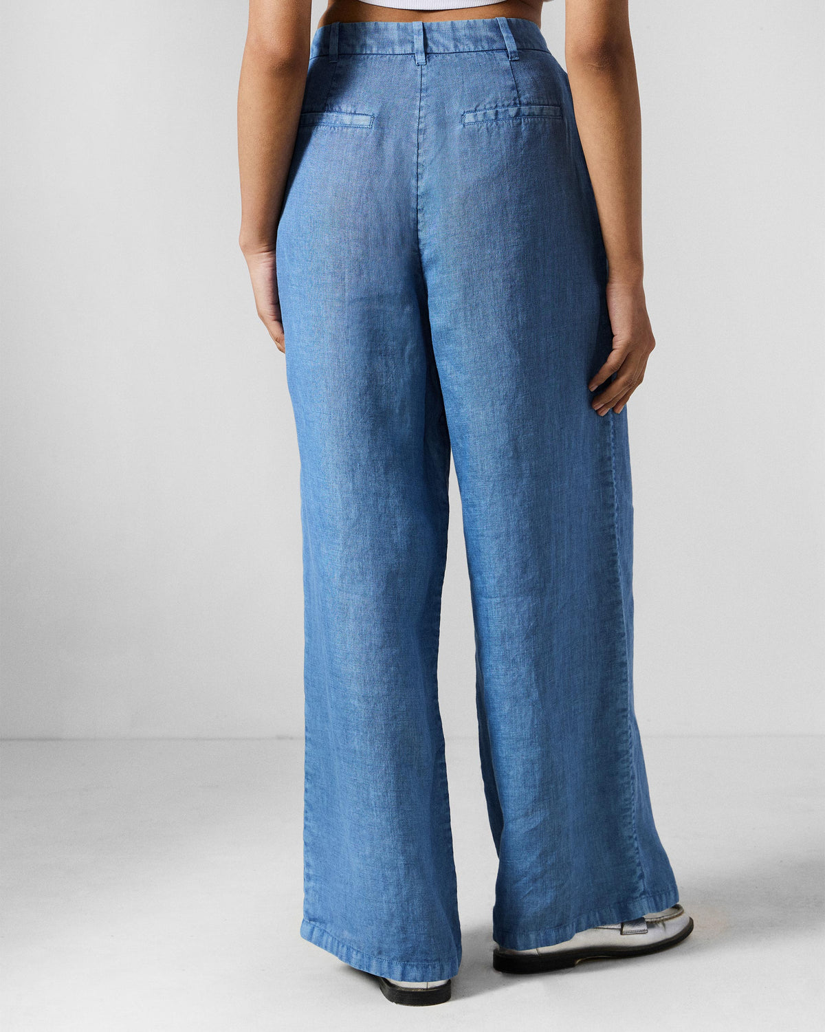 Back of blue wide-leg Aven pants with welt pockets at the waist.