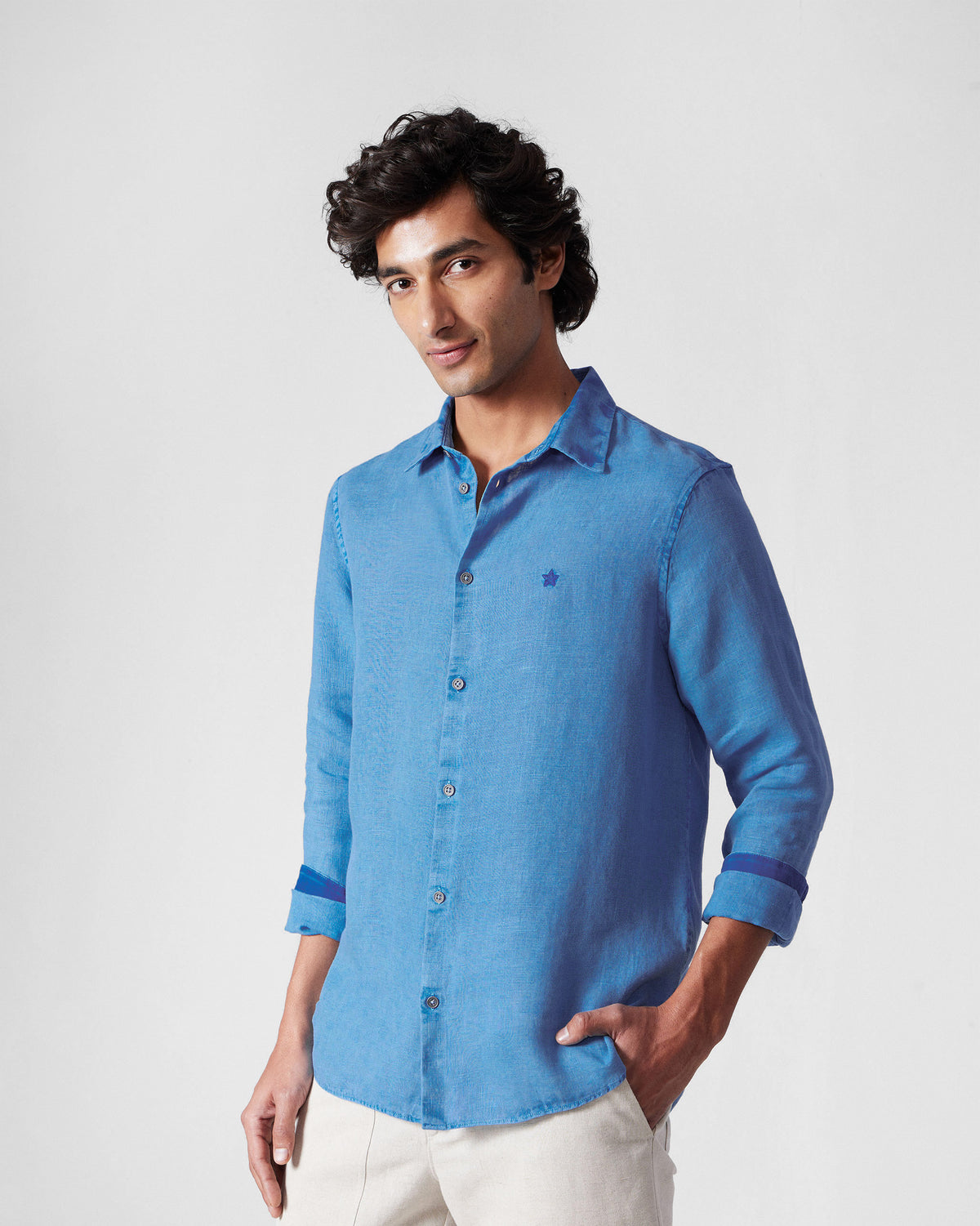 Person wearing a light blue Classic Shirt tucked in with a small chest star.