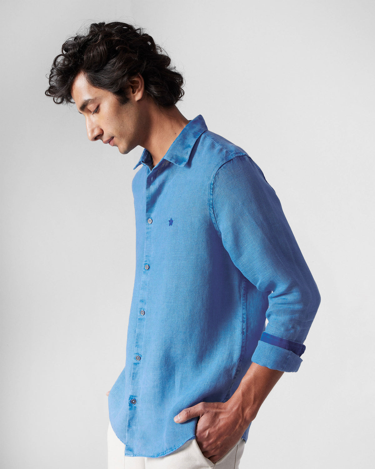 Side view of a light blue Classic Shirt showing the collar and linen drape.