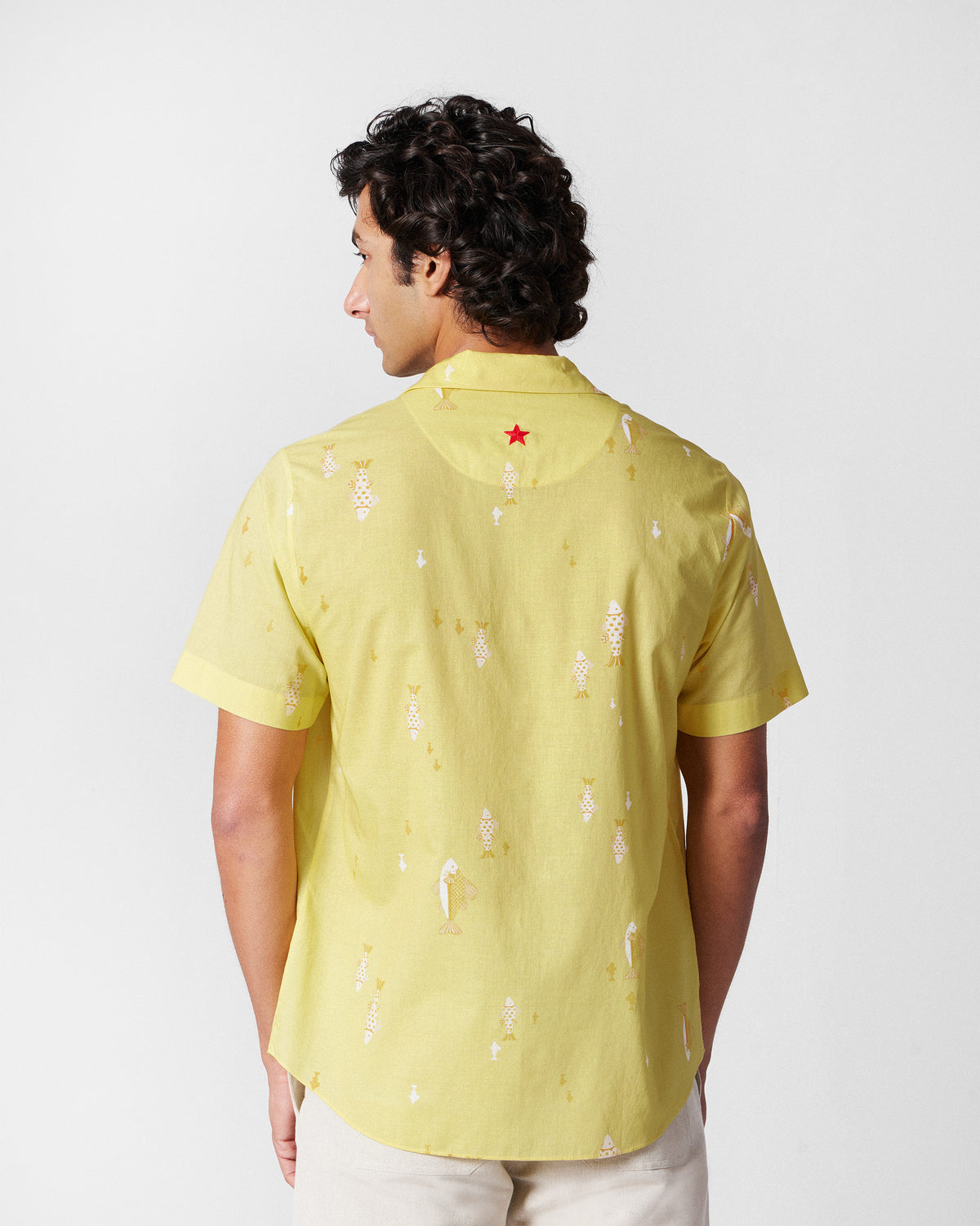 Back of a light yellow Mistari Shirt with a fish print and a red embroidered star.