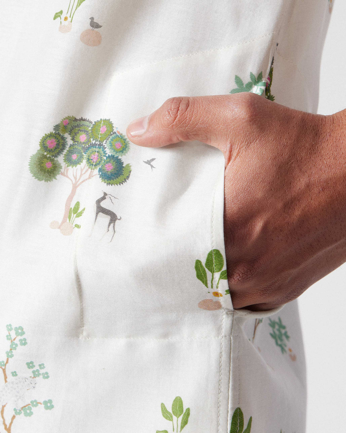 Close-up of ivory Astral kurta side pocket with green tree print.