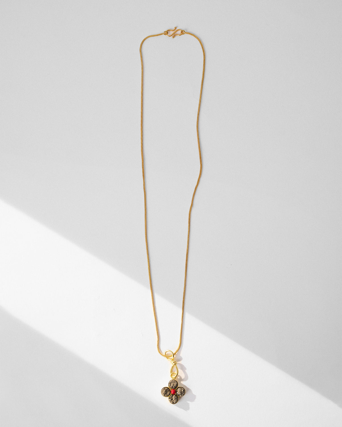 Gold Sindhu necklace laid flat with a four-petal flower pendant.