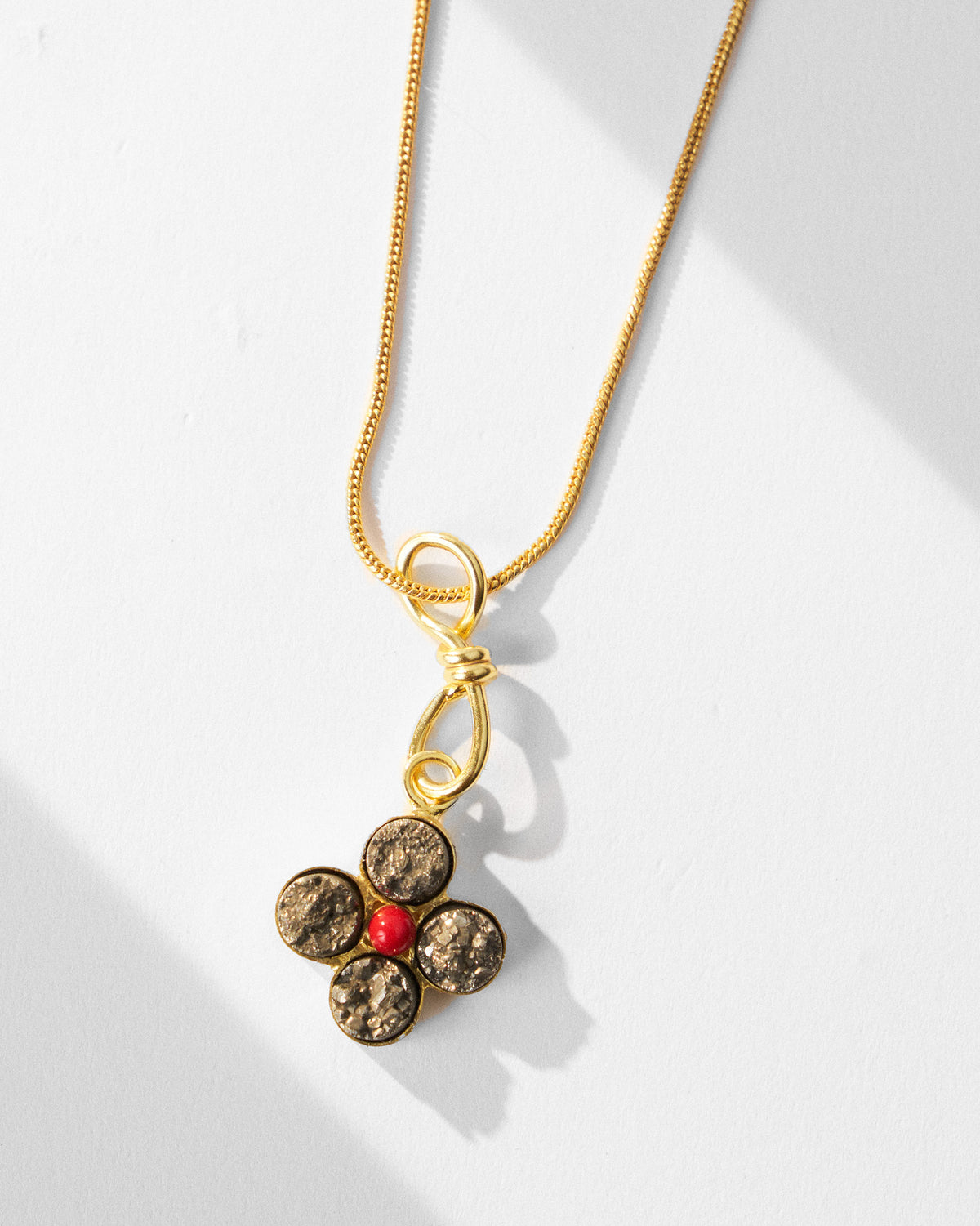 Close-up of Sindhu necklace flower pendant with dark petals and a red centre.