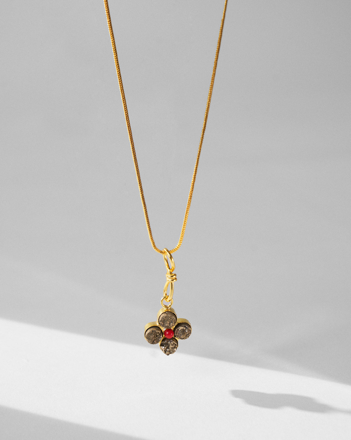 Gold Sindhu necklace hanging to show the four-petal flower pendant.