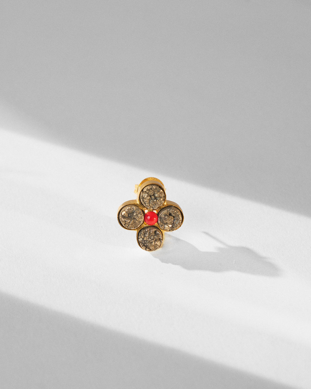 Close-up of a Sindhu gold ring with four grey stones and a red centre.