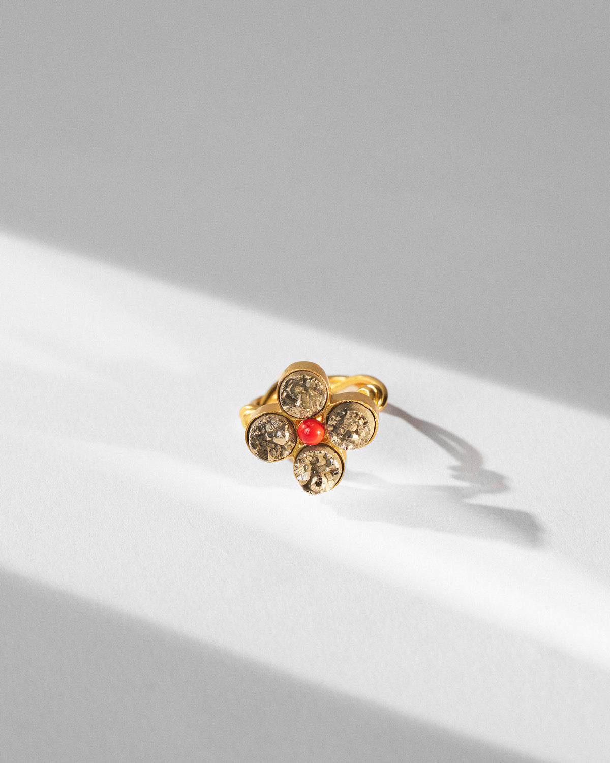 Sindhu gold flower ring with champagne-grey stones and a red centre.