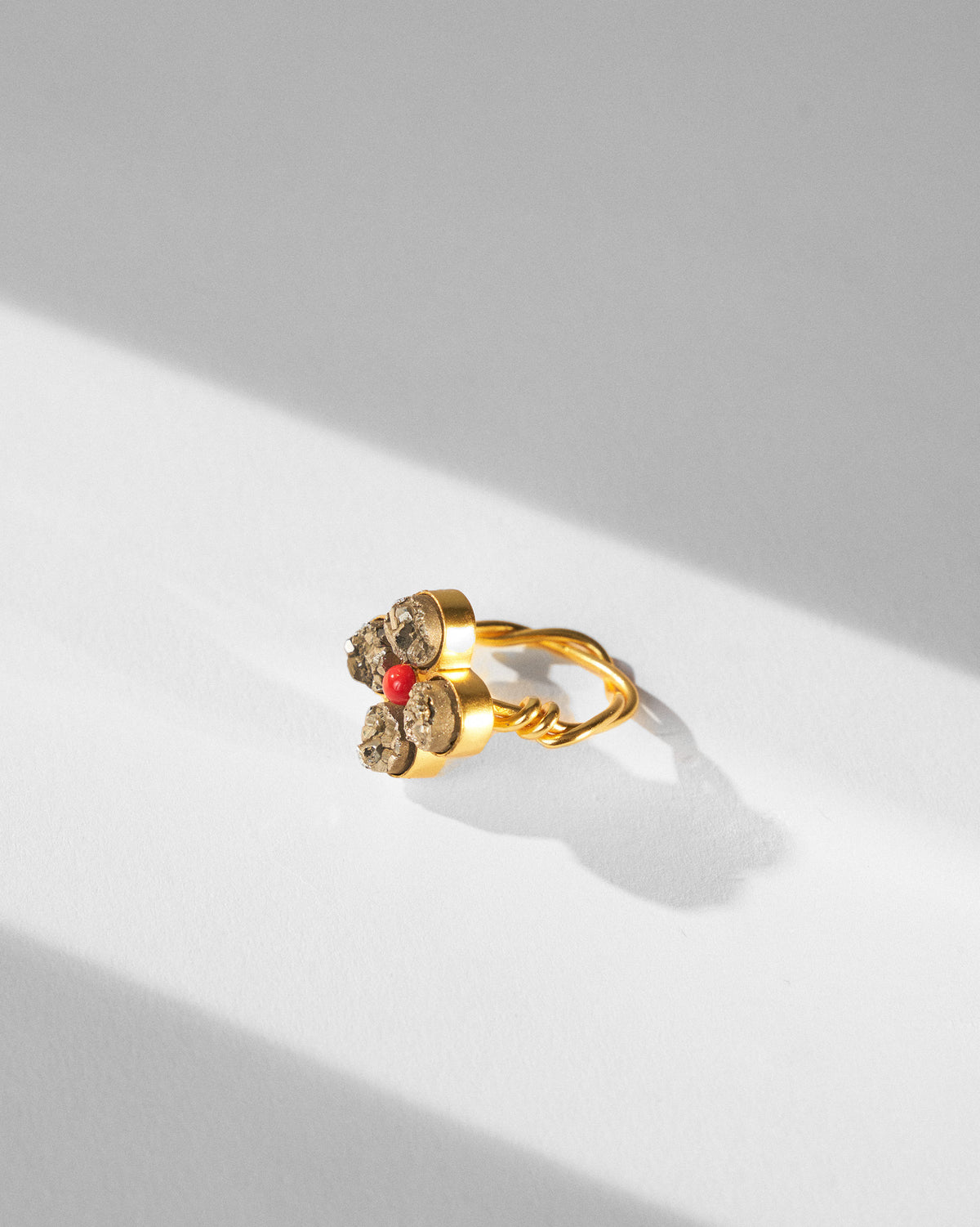 Sindhu gold flower ring with a twisted wire band and red centre bead.