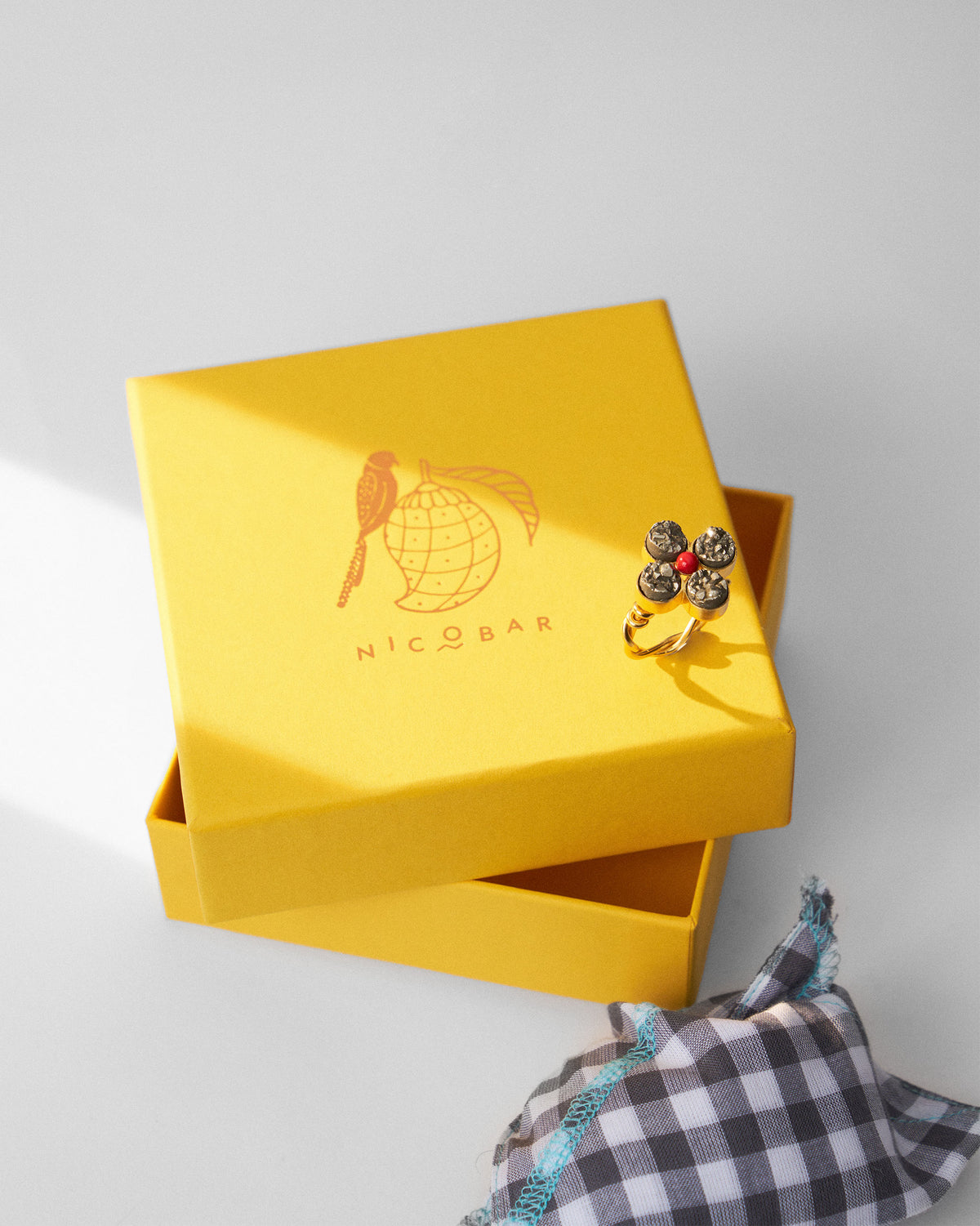 Sindhu gold flower ring on a yellow Nicobar jewellery box.