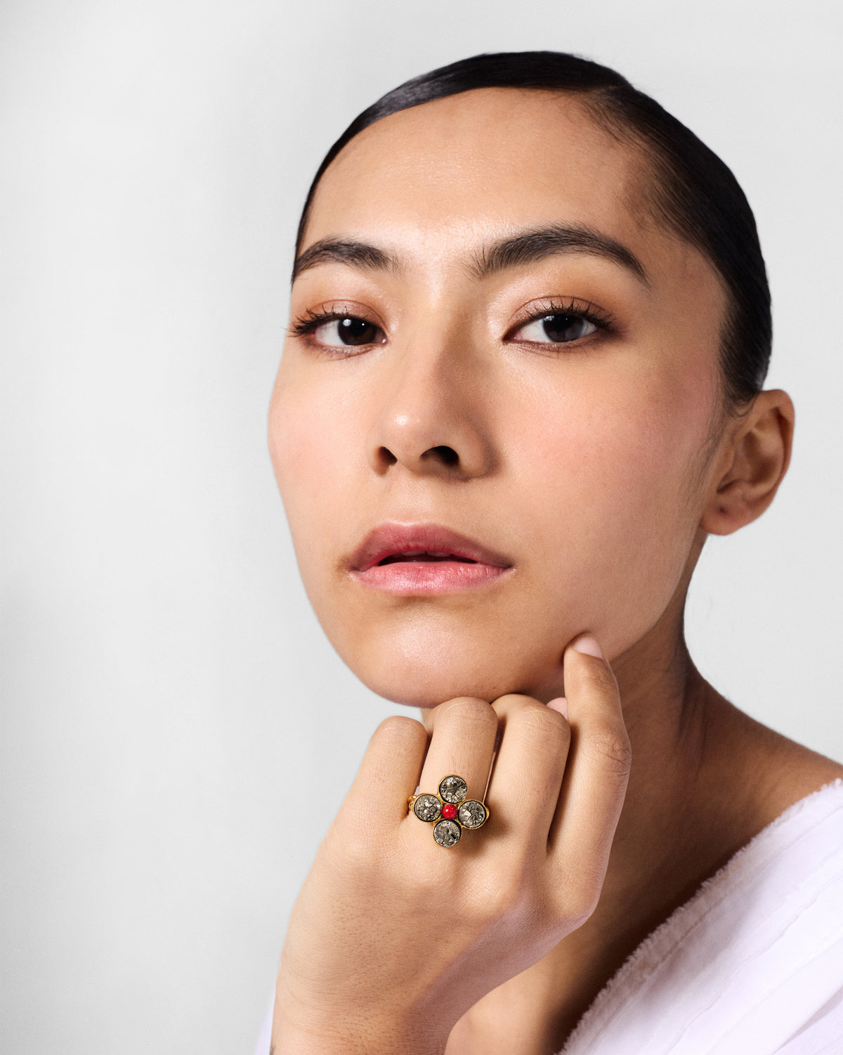 Person wearing a Sindhu gold flower ring with a red centre bead.