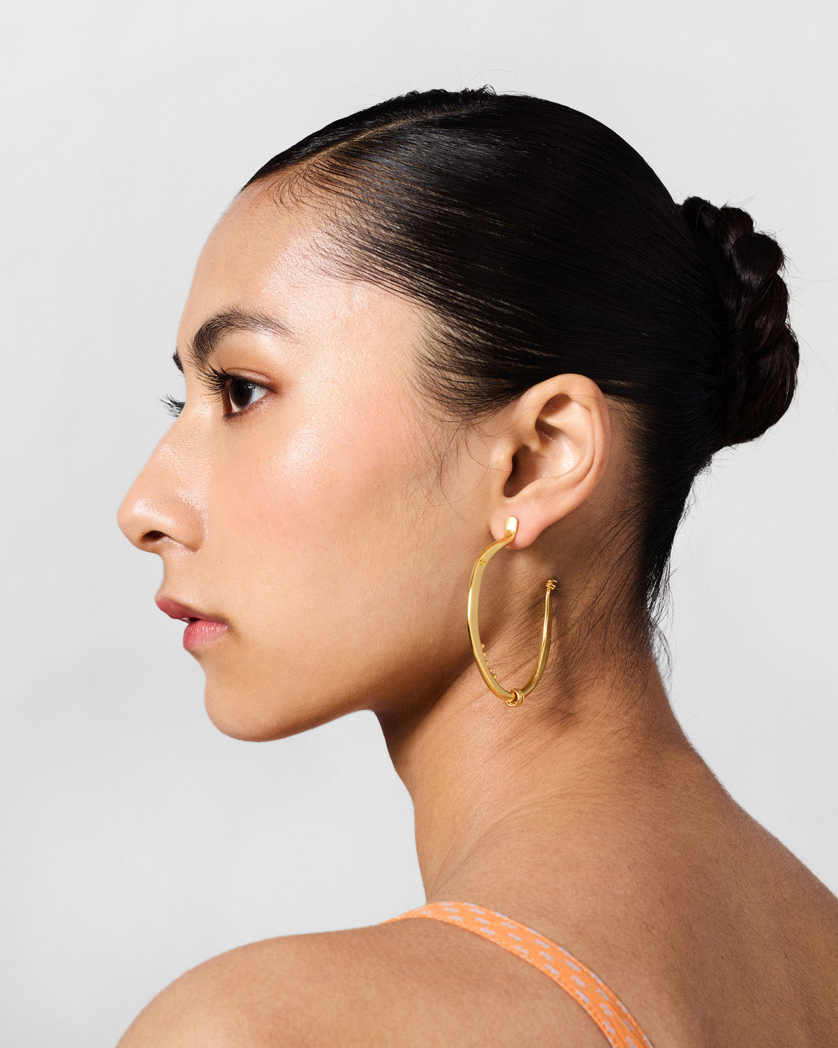 Side profile of large gold Qala balis worn by a person.