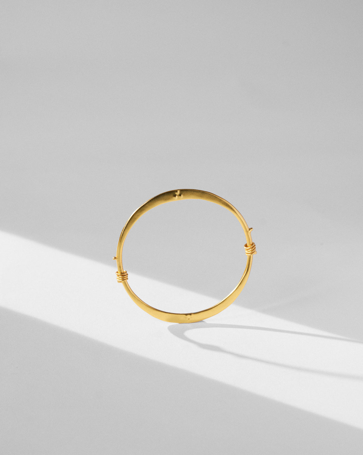 Gold qala bangle standing upright on a light surface.