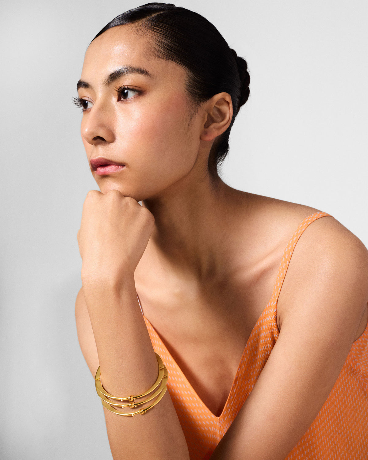Person wearing stacked gold qala bangles on a wrist.