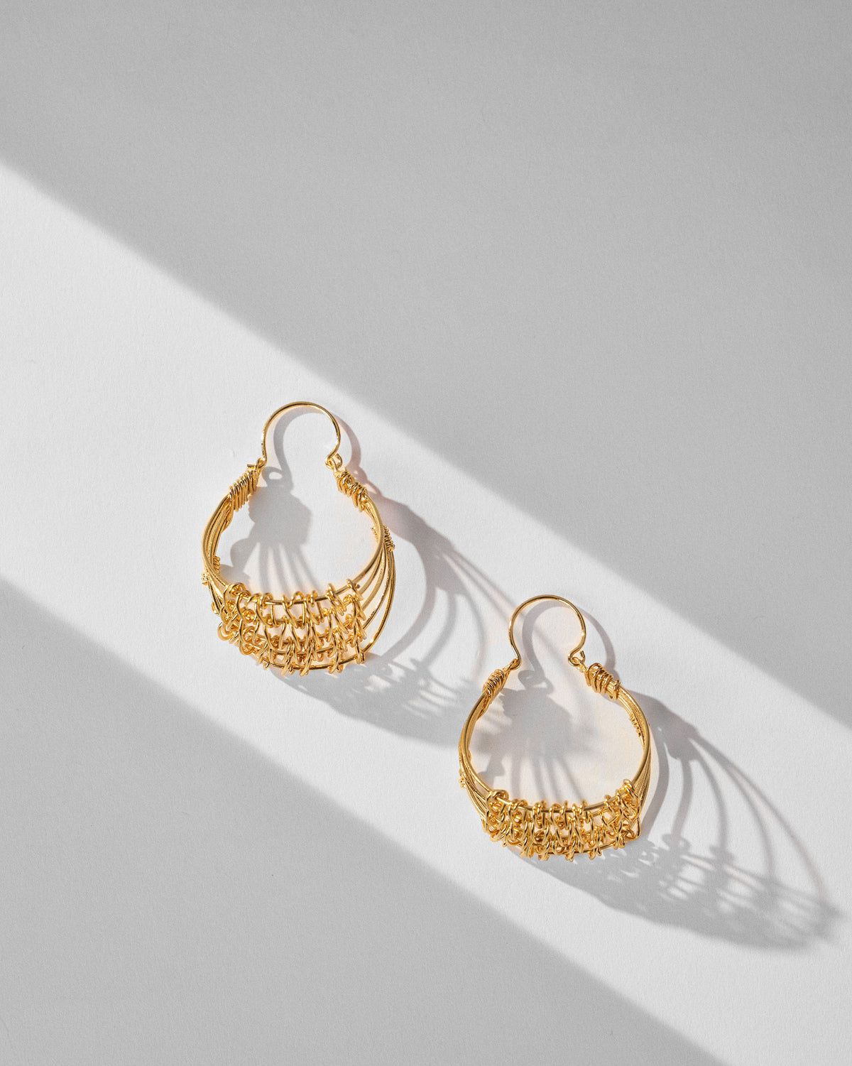 Pair of gold Shore wire balis with woven mesh laid flat.