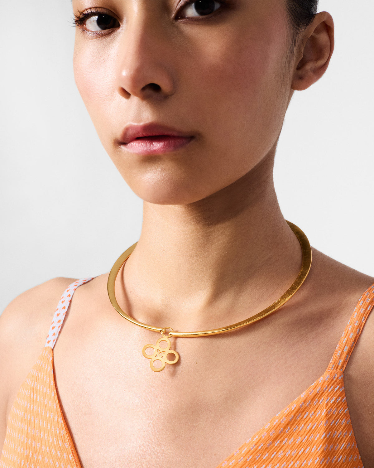 Gold sindhu choker with a floral pendant worn at the neck.