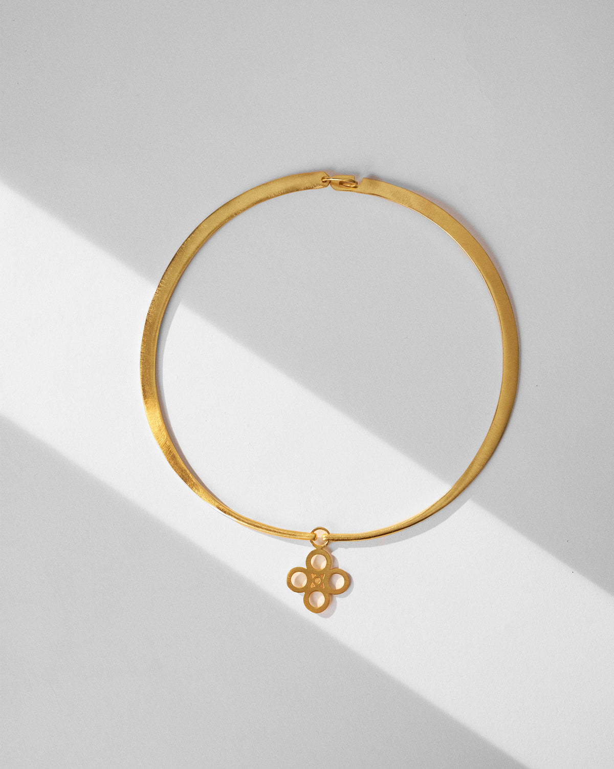 Gold sindhu choker laid flat with a quatrefoil floral pendant.