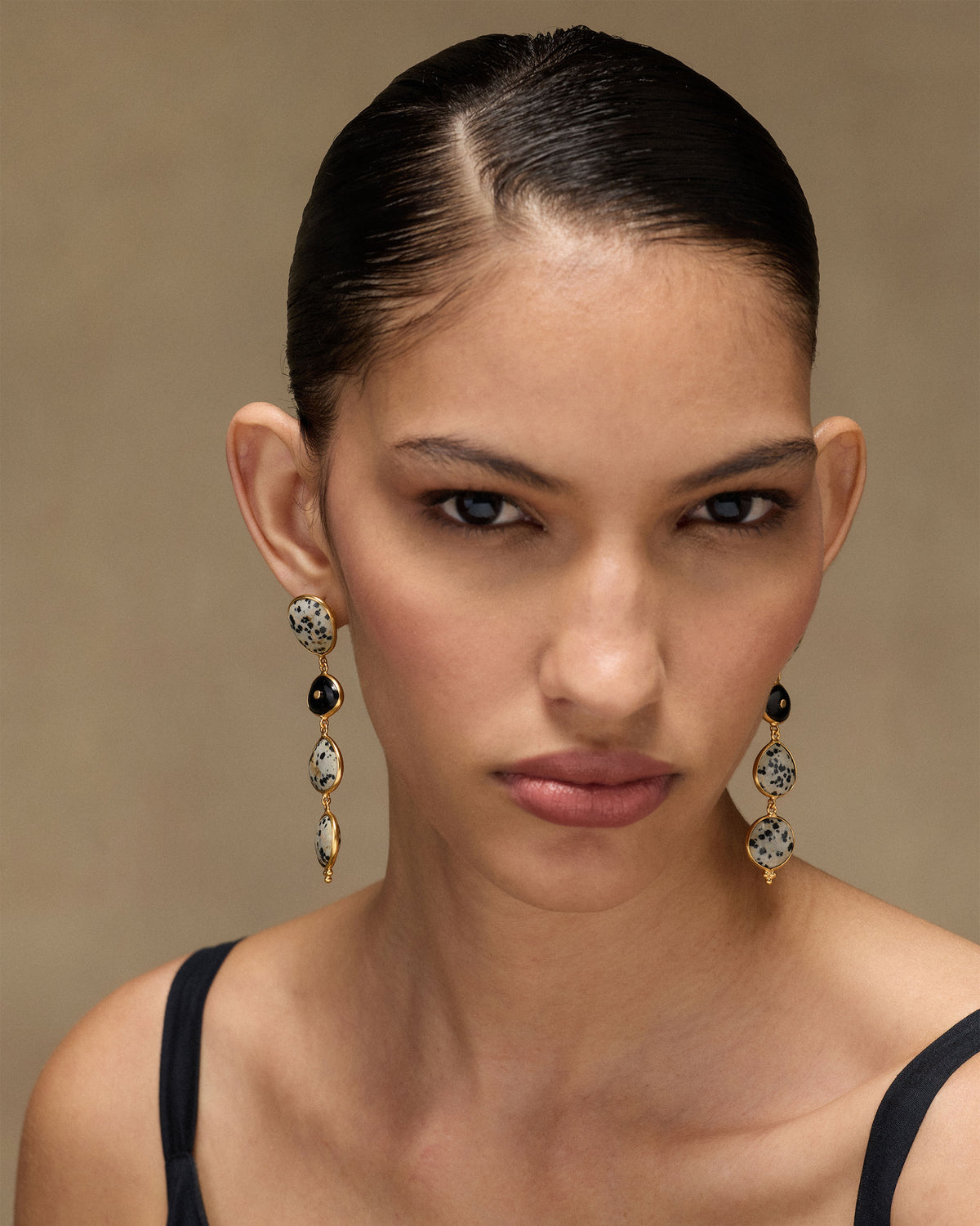 Portrait of a person wearing gold Mountain Danglers with speckled stones.