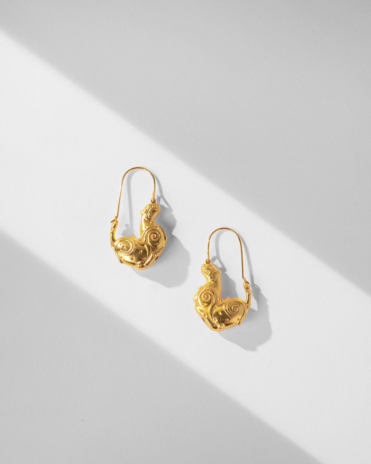 Pair of gold leopard hoop earrings laid flat.