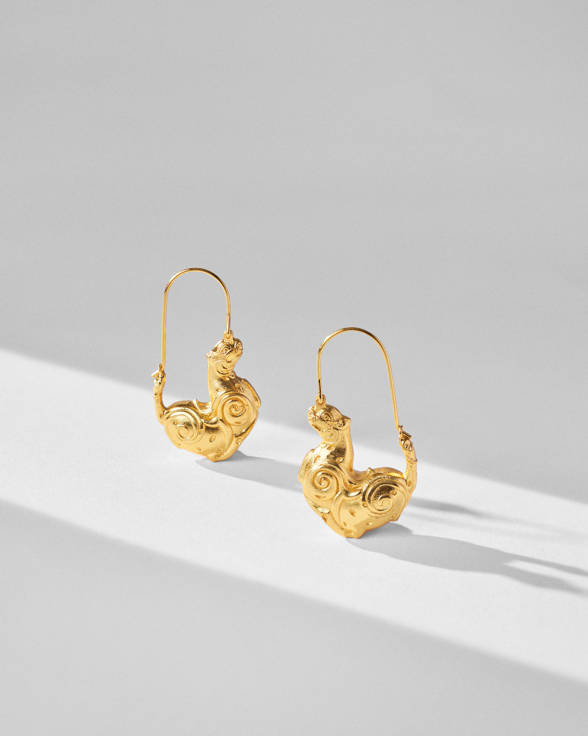 Pair of gold leopard earrings showing sculpted spiral detail.