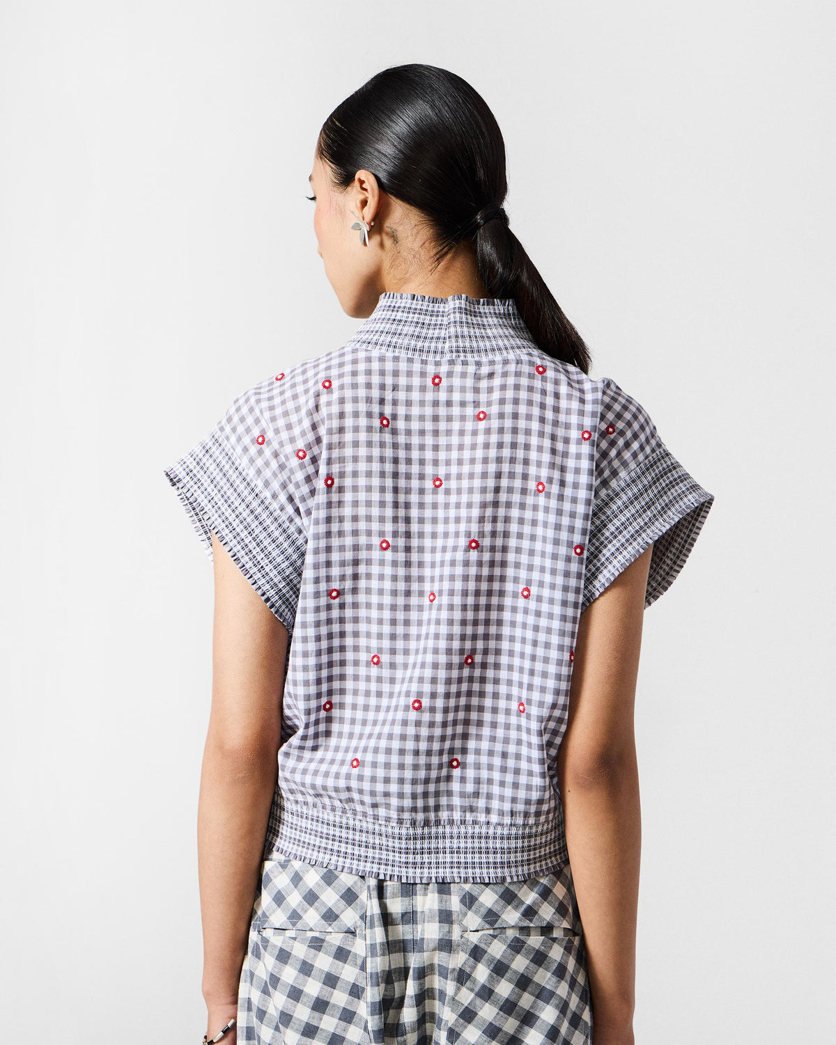 Back of a grey and white Lehar top with red embroidery and a smocked waist.