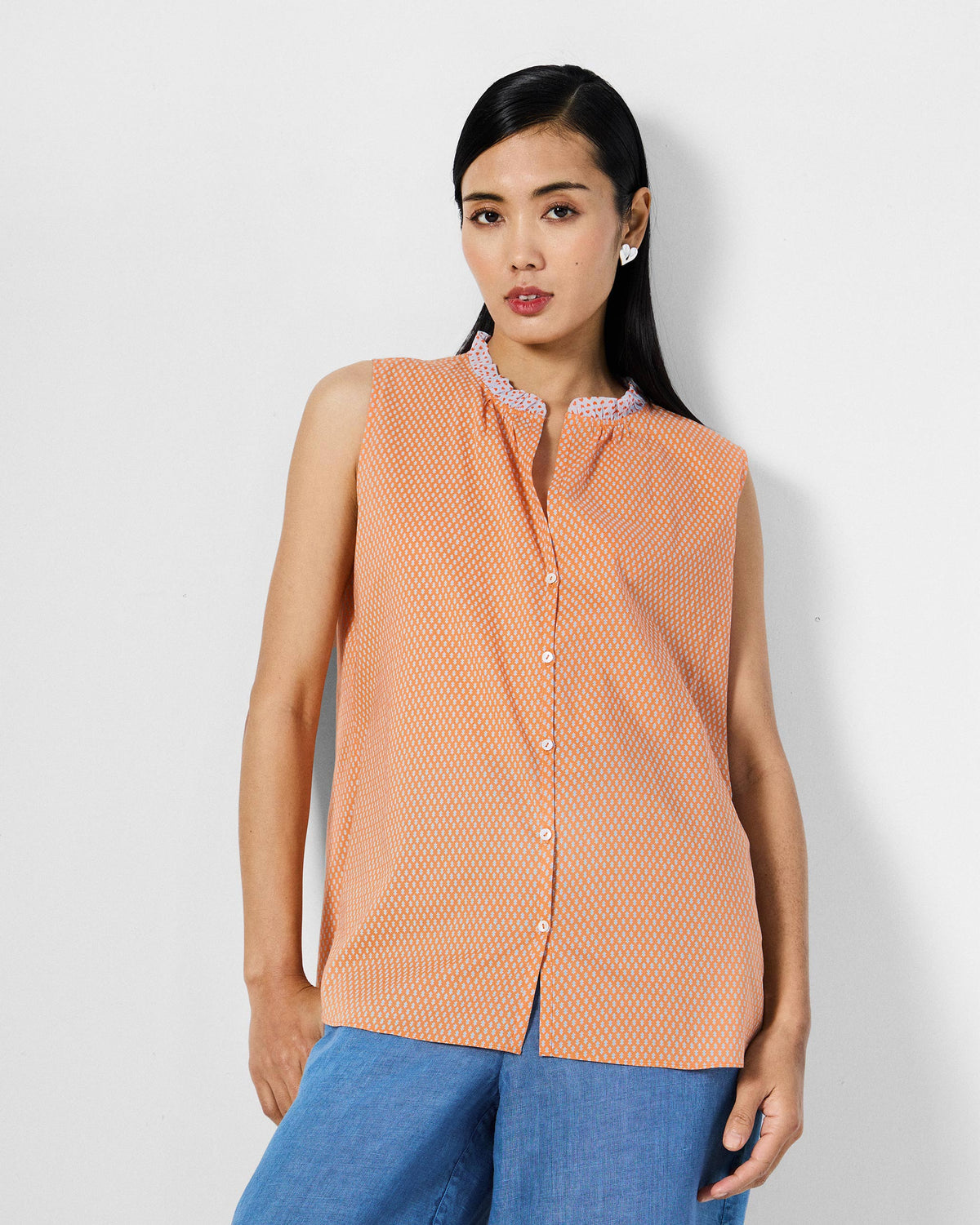 Person wearing an orange printed Roh top with a ruffle collar.