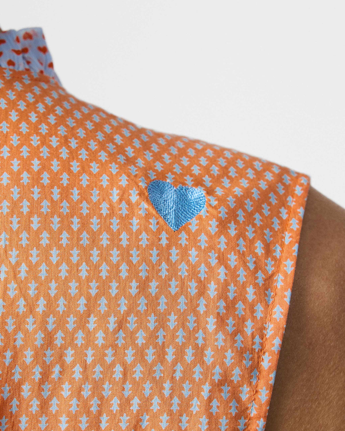 Close-up of a blue heart on an orange printed Roh top.