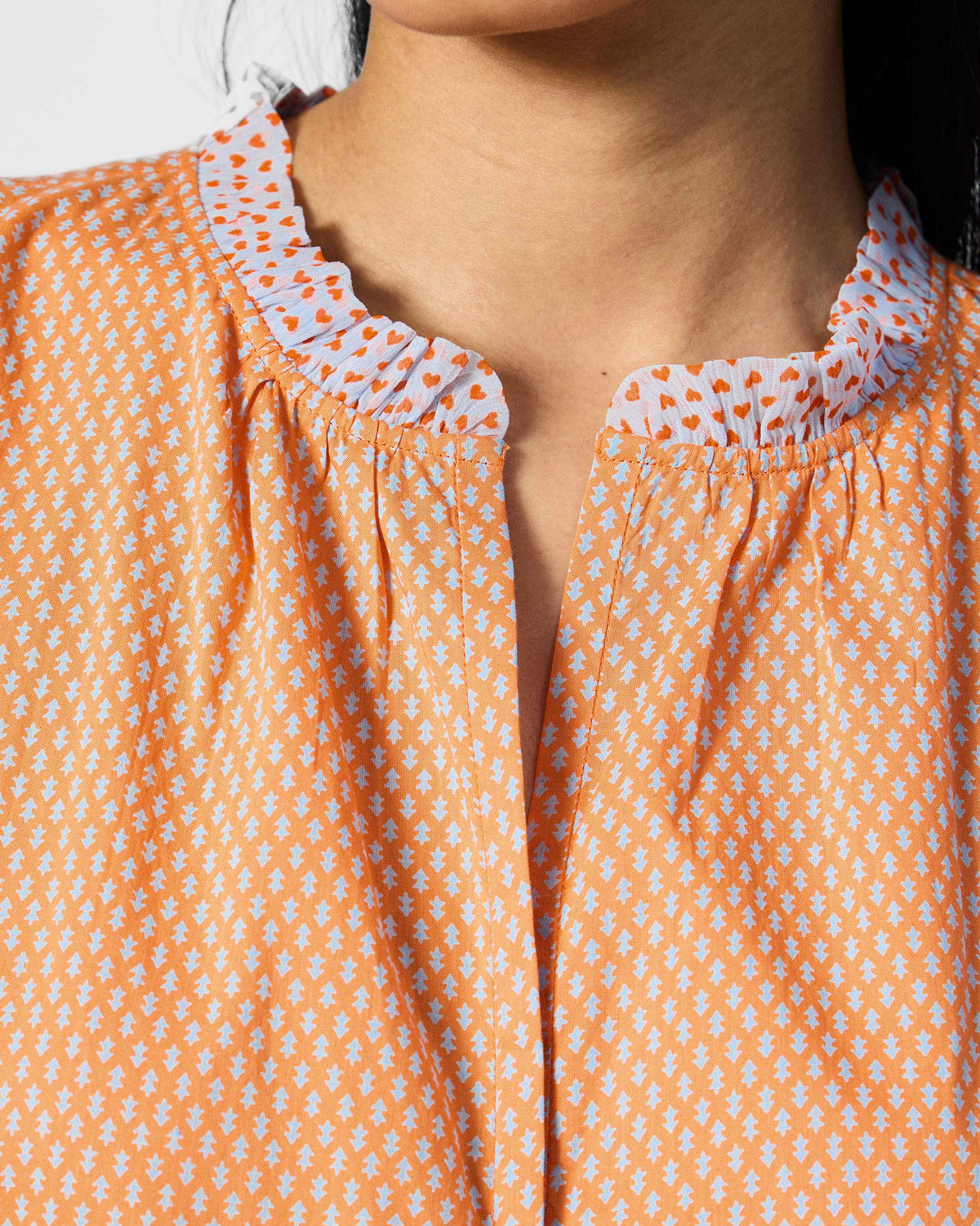 Close-up of the ruffle collar on an orange printed Roh top.