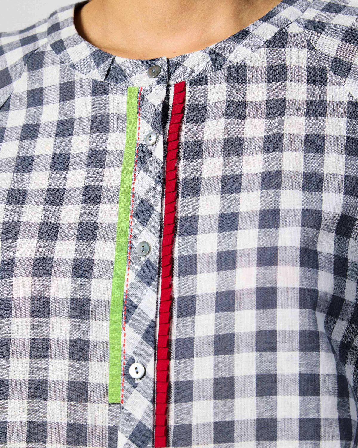 Close-up of the red and lime placket trim on a charcoal and white checked Zil top.